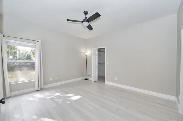 an empty room with a window and a ceiling fan