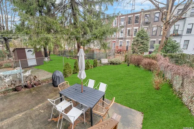 a view of a backyard with table and chairs potted plants and large tree