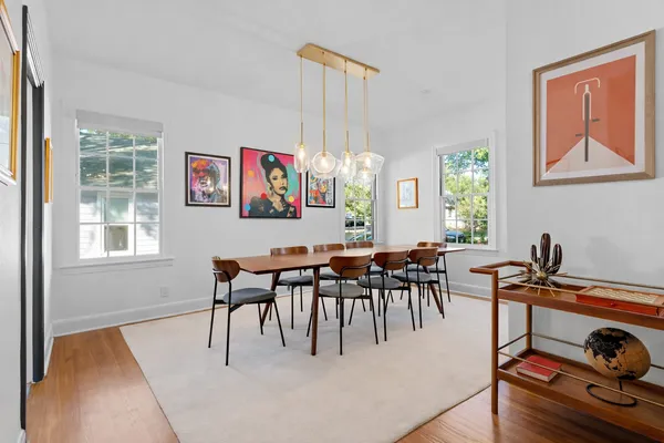 a dining room with wooden floor a chandelier a wooden table and chairs
