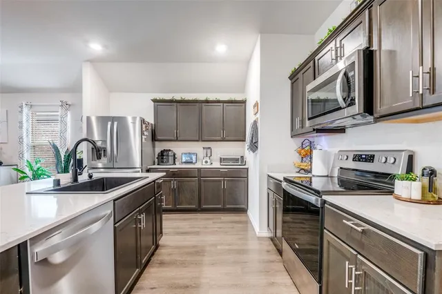a kitchen with stainless steel appliances granite countertop a sink dishwasher stove and microwave with wooden cabinets