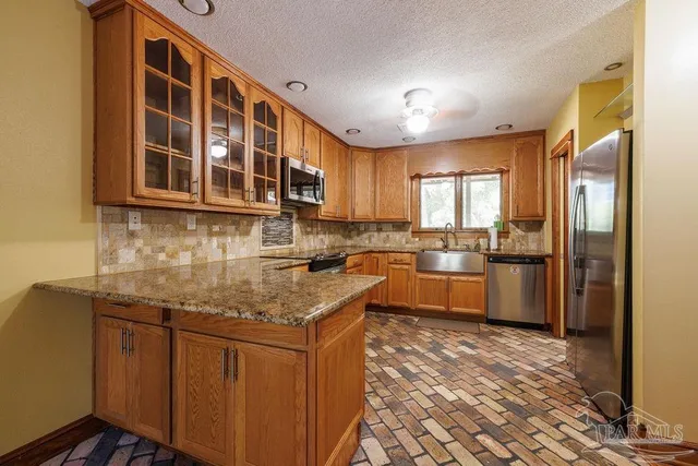 a kitchen with stainless steel appliances granite countertop a stove a sink dishwasher a refrigerator and cabinets with wooden floor