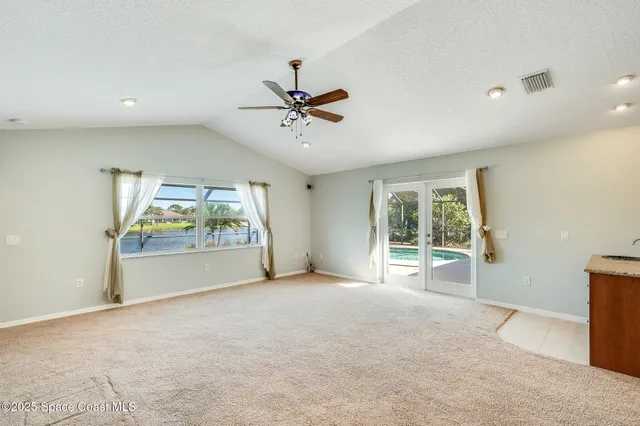 an empty room with ceiling fan and window
