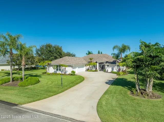 a view of a house with a big yard plants and large trees