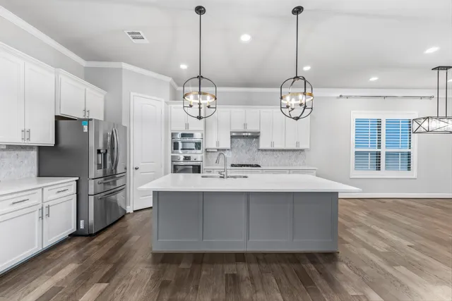 a large kitchen with stainless steel appliances a large center island attached withe living room