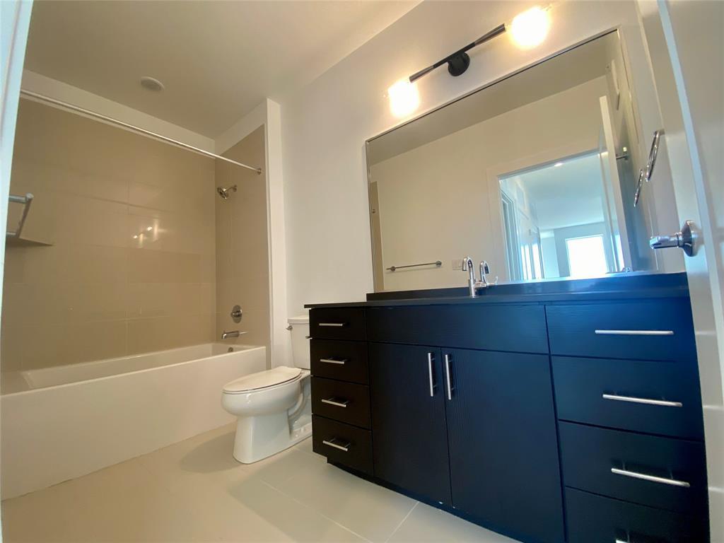 4801 Springdale Road, Unit 2408 Austin, TX 78723 - Photo 13 of 22 a bathroom with a granite countertop toilet a sink and a mirror