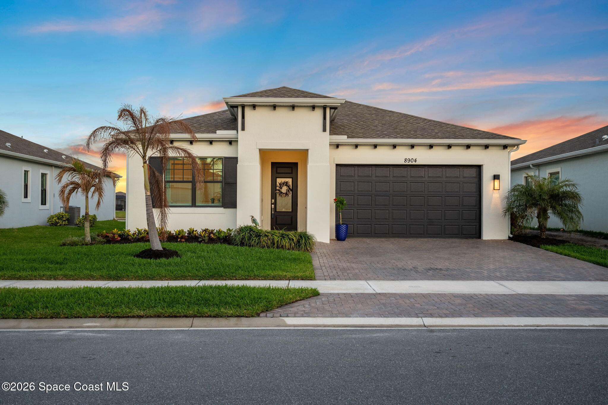 8904 Alister Drive Melbourne, FL 32940 - Photo 2 of 91 a front view of a house with a garden and garage