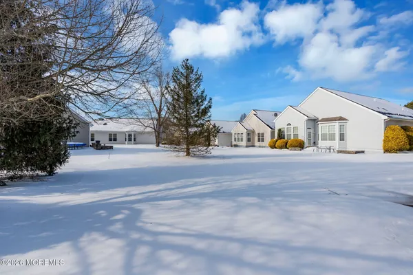 a view of white house with a big yard and large trees