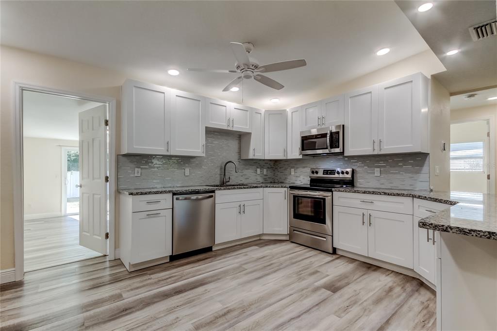 1353 Mary L Road Clearwater, FL 33755 - Photo 10 of 44 a kitchen with granite countertop white cabinets and white appliances