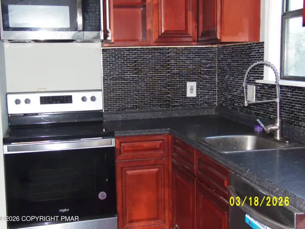 a kitchen with granite countertop a sink stove and cabinets