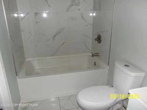 a white toilet sitting next to a bath tub