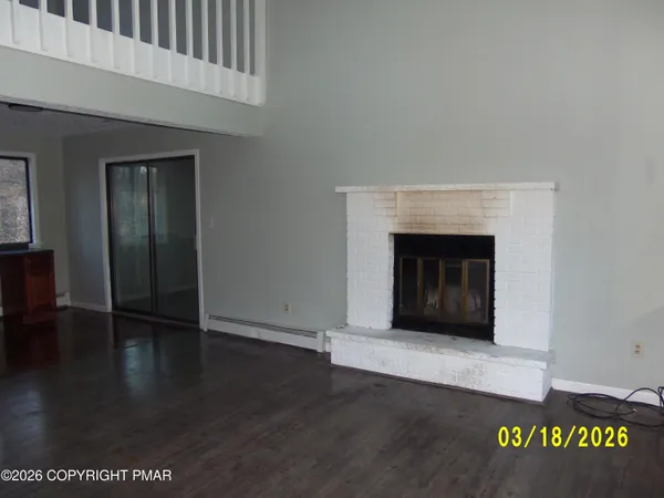 a view of an empty room with wooden floor and a fireplace