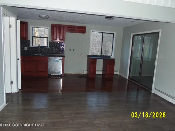 a view of a hallway with wooden floor and a living room