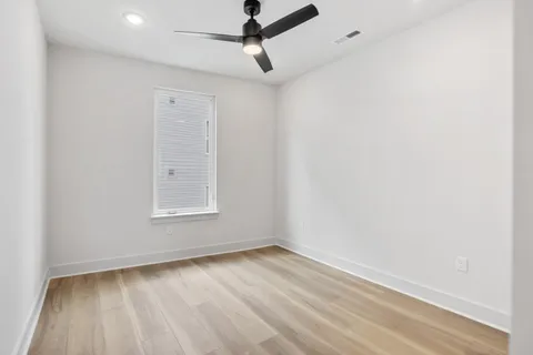 an empty room with a window and ceiling fan