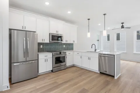 a kitchen with white cabinets stainless steel appliances and wooden floor