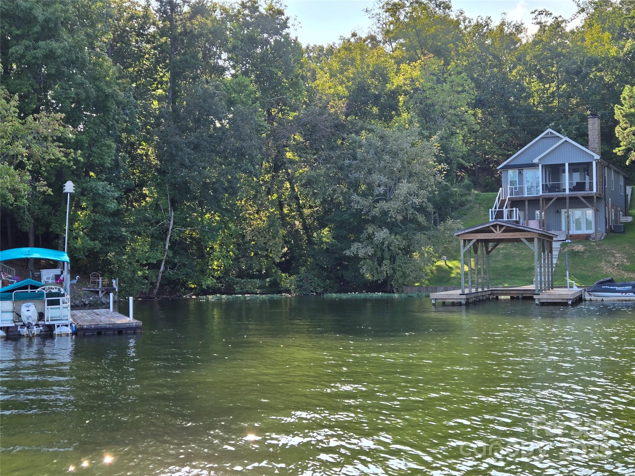 0 Shoreline Road, Unit 107 Badin Lake, NC 28127 - Photo 36 of 48 a view of a house next to a lake with a large trees