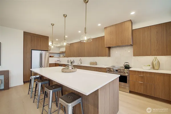 a kitchen with stainless steel appliances kitchen island granite countertop a sink a stove and a wooden floors