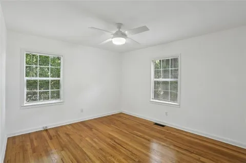 an empty room with wooden floor and windows