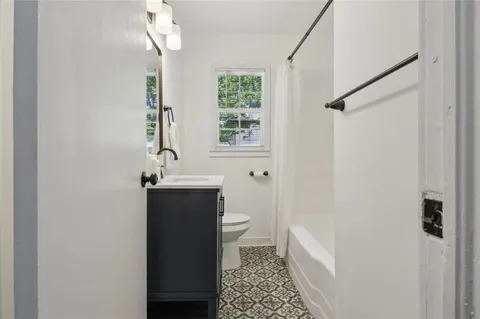 a bathroom with a sink a toilet a window and shower