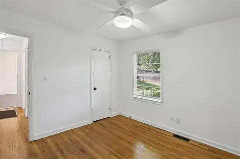 an empty room with wooden floor closet and windows
