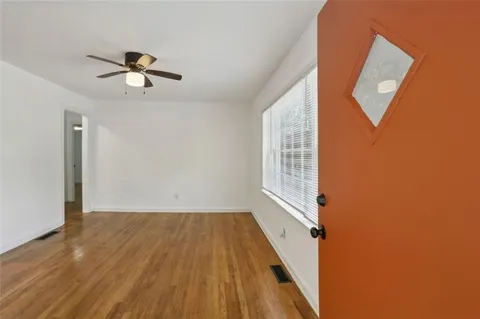 a view of empty room with wooden floor and fan