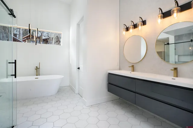 a bathroom with a double vanity sink mirror and bathtub