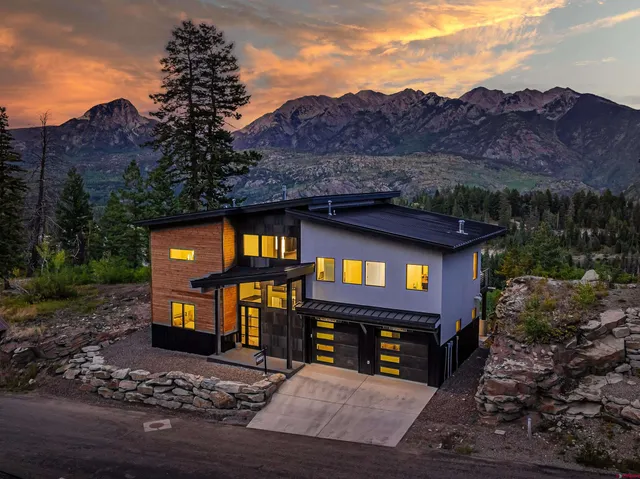 a view of a house with a yard and a large tree