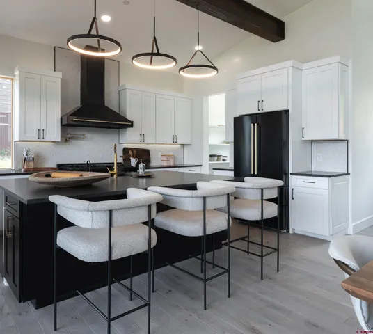 a kitchen with stainless steel appliances a dining table chairs refrigerator and sink