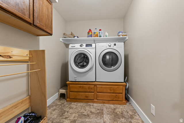 4557 North Ranch Road East Tooele, UT 84074 - Photo 14 of 43 Laundry area featuring wood-finish cabinetry, a built-in wood-finish drying rack, a white wall shelf, and tiled flooring
