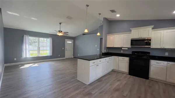 a kitchen with granite countertop a stove top oven a sink dishwasher and a microwave oven with wooden floor