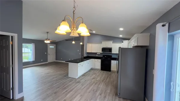 a kitchen with stainless steel appliances granite countertop a refrigerator a sink dishwasher a stove and a dining table with wooden floor