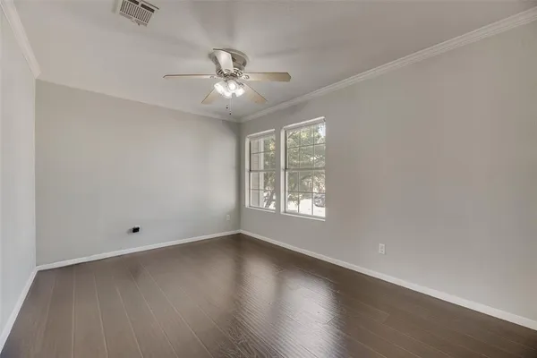 an empty room with wooden floor fan and windows