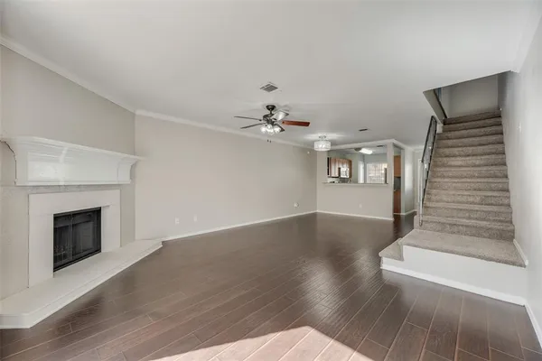 a view of an empty room with wooden floor and a fireplace