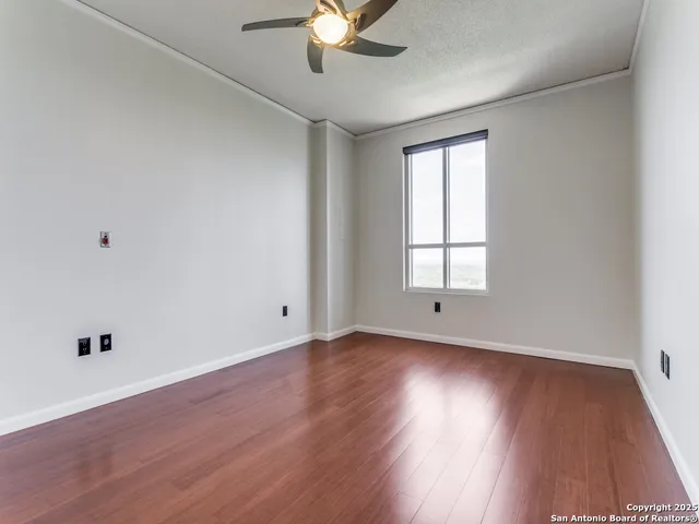 a view of an empty room with wooden floor and a window