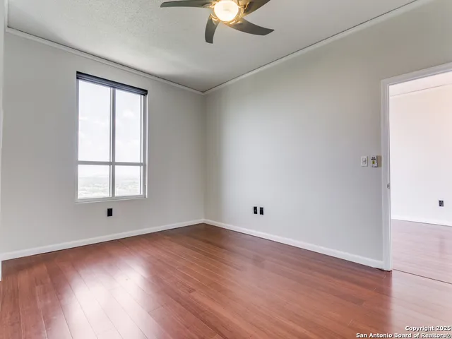 an empty room with wooden floor and windows
