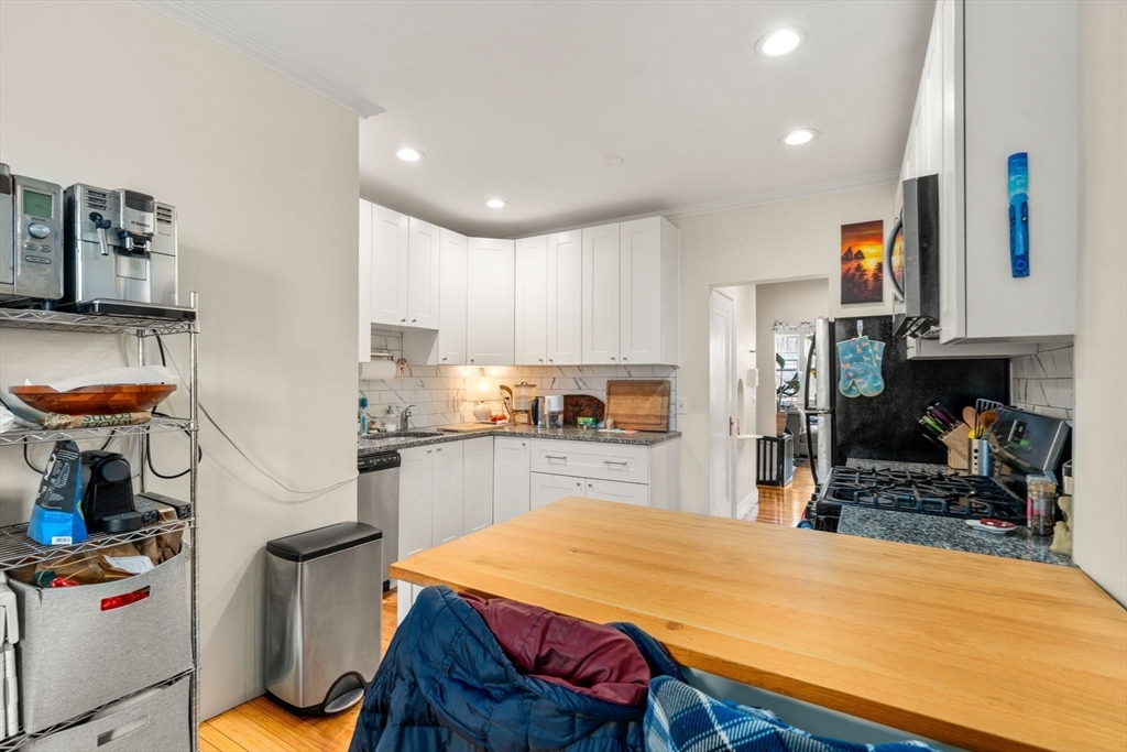 285 Corey Road, Unit 4 Boston, MA 02135 - Photo 12 of 26 a kitchen with stainless steel appliances kitchen island sink stove refrigerator and cabinets