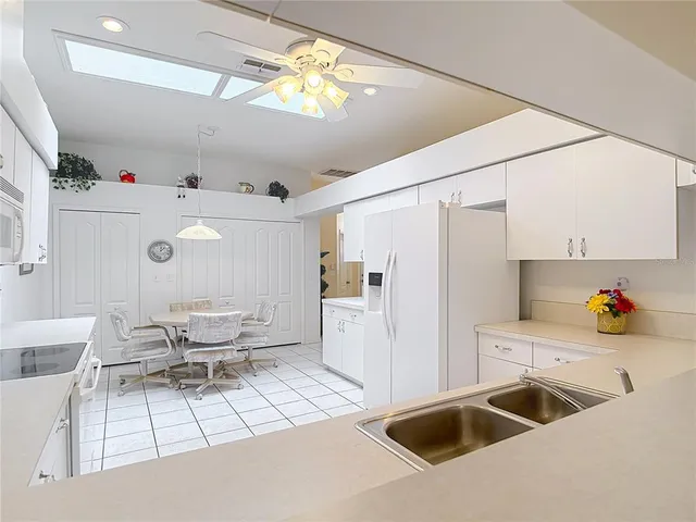 a kitchen with stainless steel appliances granite countertop a sink a stove a refrigerator cabinets a dining table and chairs