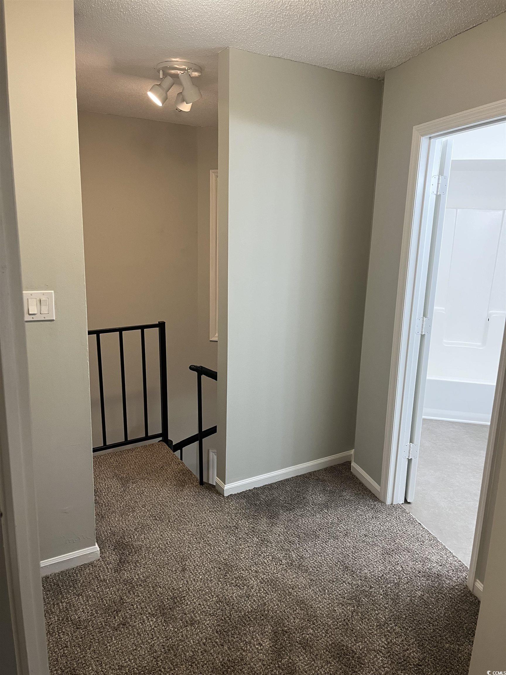 600 65th Avenue North, Unit 7 Myrtle Beach, SC 29572 - Photo 14 of 29 Hall featuring carpet flooring, a textured ceiling, and an upstairs landing