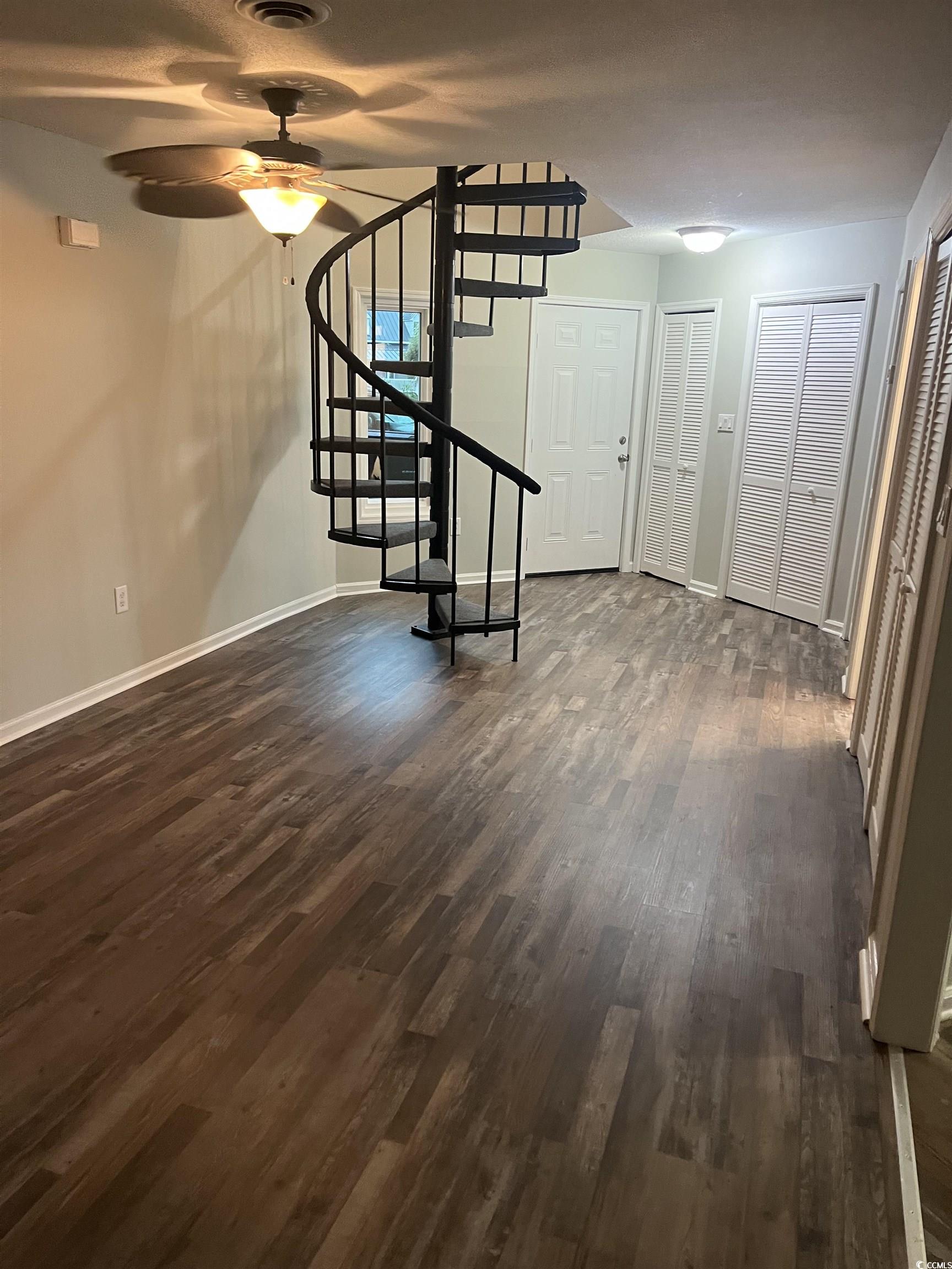 600 65th Avenue North, Unit 7 Myrtle Beach, SC 29572 - Photo 5 of 29 Unfurnished living room featuring stairs, dark wood-style floors, and ceiling fan