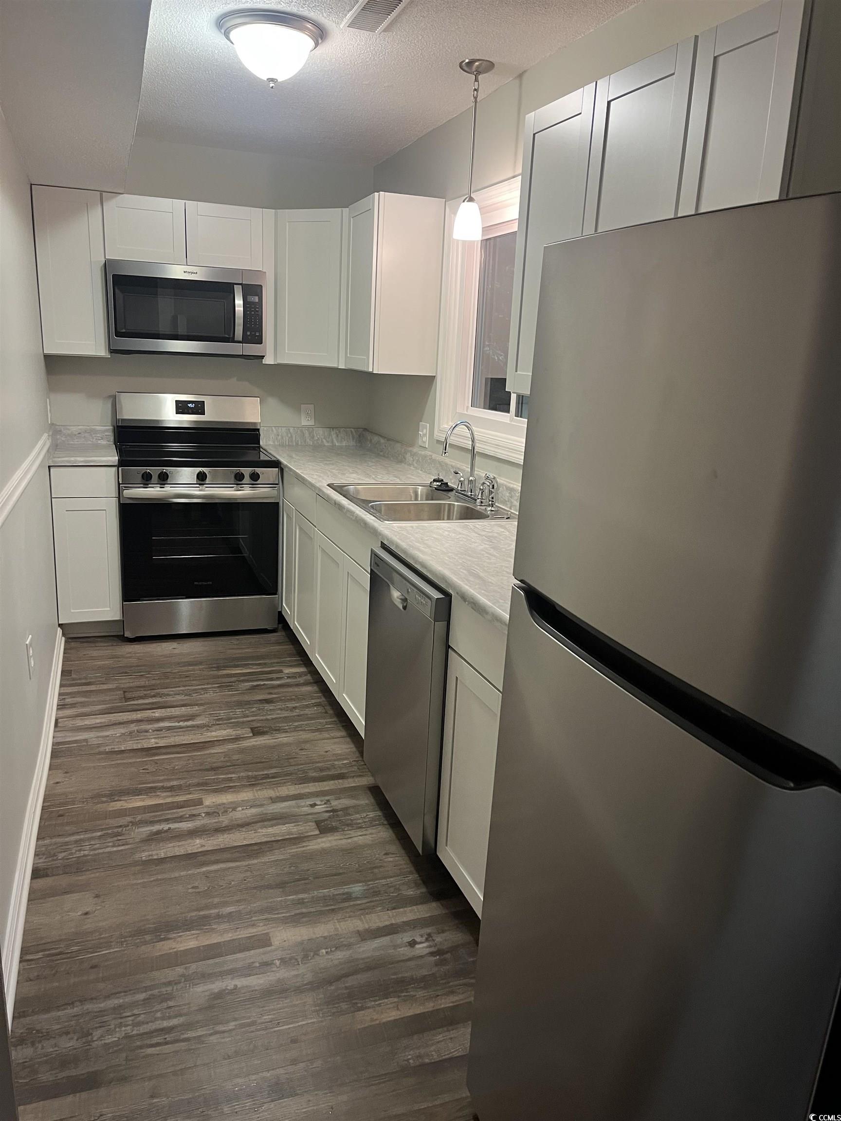600 65th Avenue North, Unit 7 Myrtle Beach, SC 29572 - Photo 7 of 29 Kitchen featuring stainless steel appliances, white cabinets, light countertops, a textured ceiling, and pendant lighting
