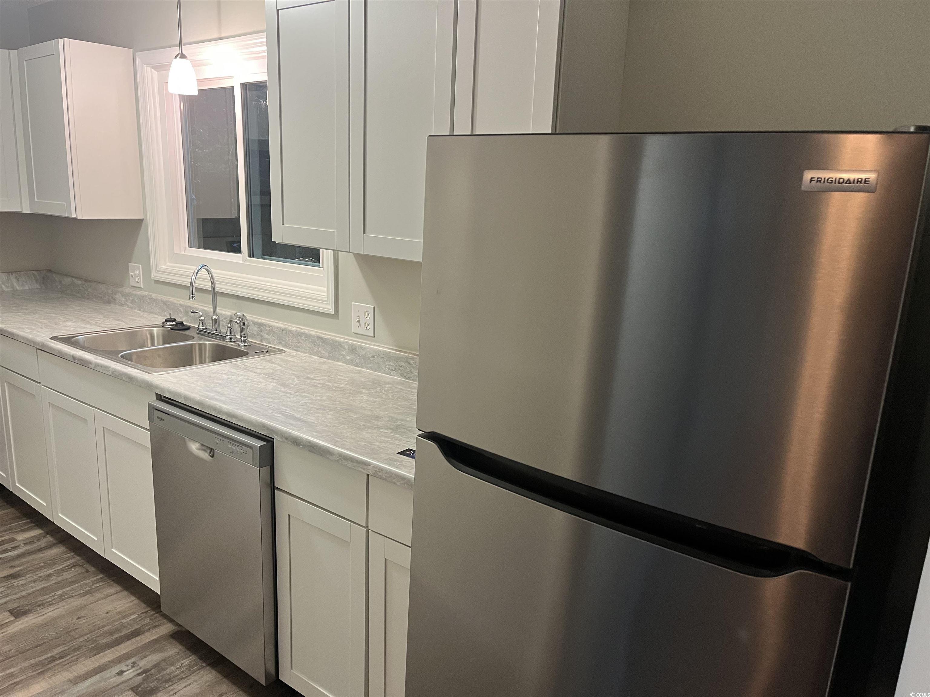 600 65th Avenue North, Unit 7 Myrtle Beach, SC 29572 - Photo 8 of 29 Kitchen with appliances with stainless steel finishes, light countertops, white cabinets, and dark wood-style flooring