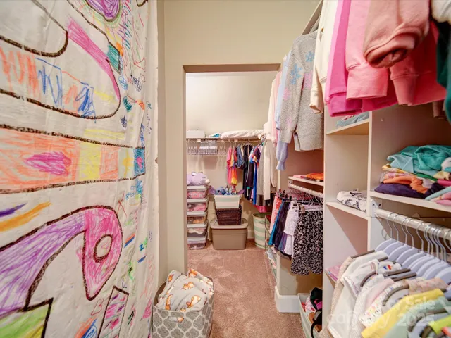 a view of walk in closet with clothes and shoes