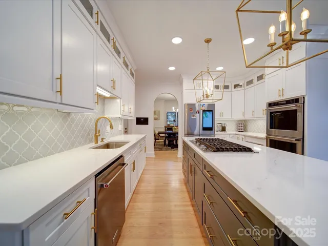 a large kitchen with stainless steel appliances granite countertop a sink a stove and a wooden floors