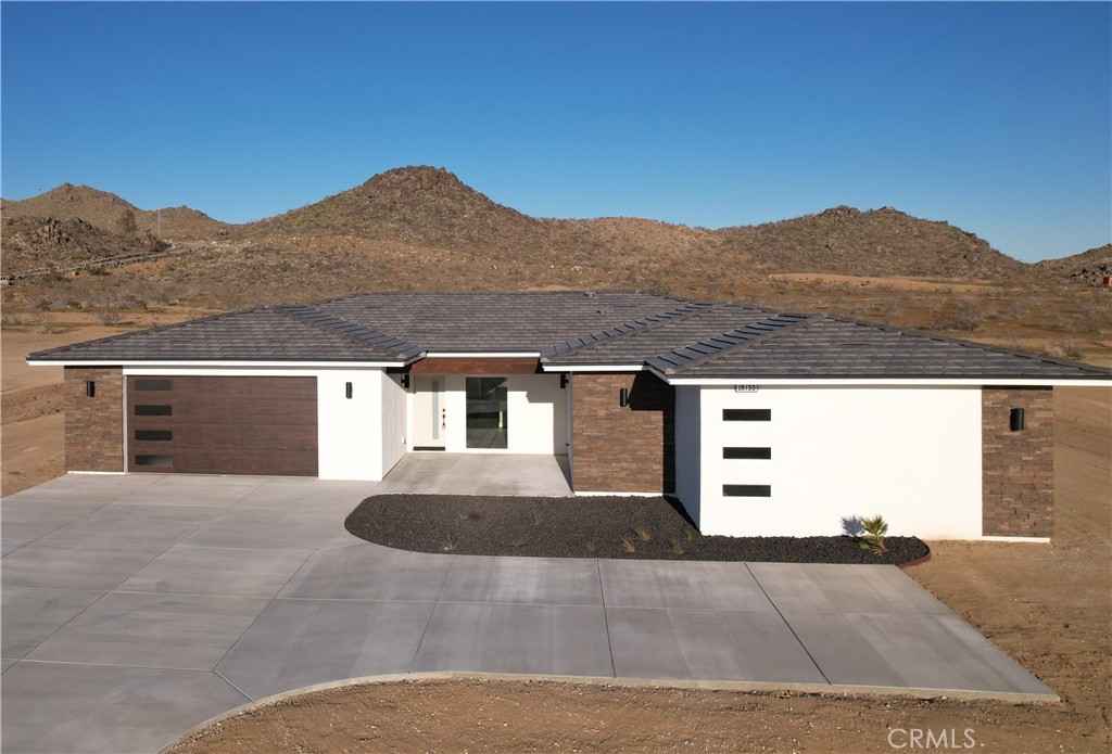 a front view of a house with a yard and mountain