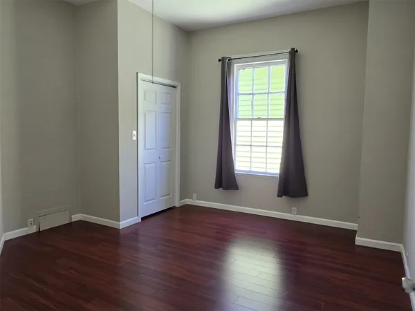 an empty room with wooden floor and windows