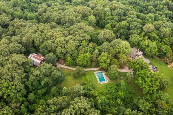 an aerial view of residential house with outdoor space and trees all around