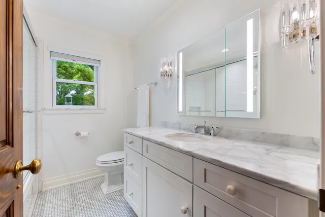 a bathroom with a granite countertop sink a toilet and a mirror