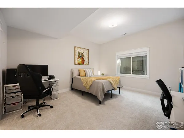 a bedroom with a bed a computer on the desk and chair