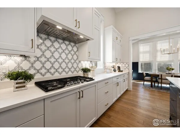 a kitchen with white cabinets and wooden floor