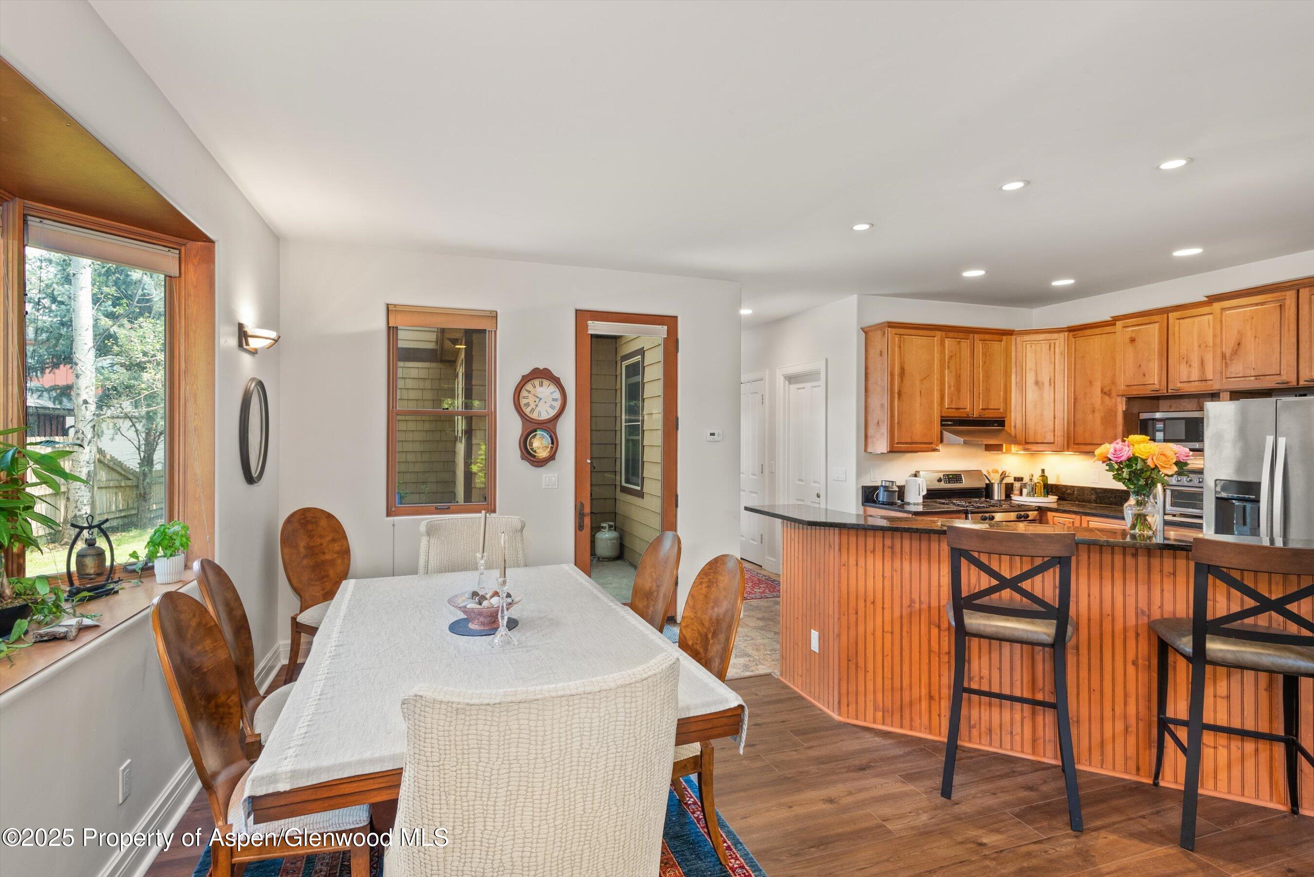 315 Summerset Lane, Unit A Basalt, CO 81621 - Photo 16 of 18 a kitchen with stainless steel appliances kitchen island granite countertop a stove a sink a dining table and chairs with wooden floor