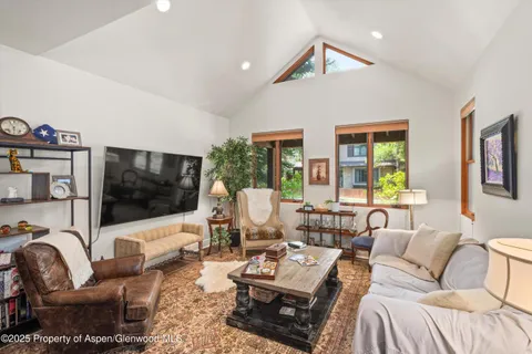 a living room with furniture a flat screen tv and a large window